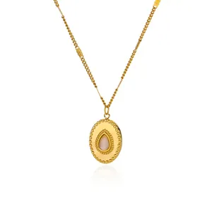 Close-up of golden oval pendant with pink resin stone and vintage beaded metal texture