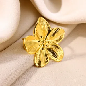 Macro shot of gold flower brooch with brushed metal texture on soft silk fabric