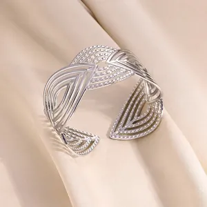 Détail d'un bracelet manchette évidé argenté avec texture ondulée sur tissu de soie beige
