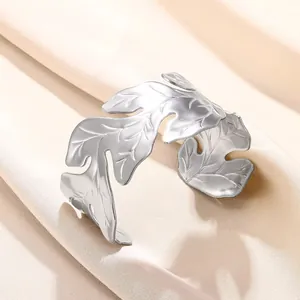 Détail d'un large bracelet manchette argenté avec texture de feuilles évidées