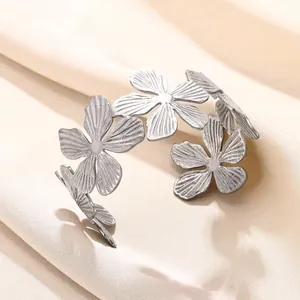 Détail d'un bracelet manchette en acier argenté avec cinq motifs de fleurs ajourées
