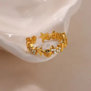 Close-up of a gold shell and starfish ring with pavé zircons on white ceramic