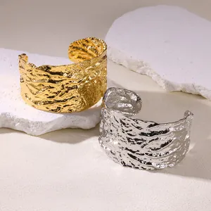 Macro view of wide cuff bracelets with irregular 18K gold and silver lava textures