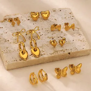 Gold heart and butterfly bow earring set displayed on natural beige stone background