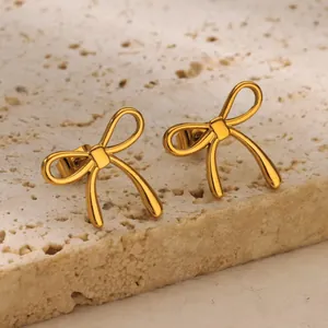 Elegant gold bow earrings made of stainless steel displayed on a natural travertine stone
