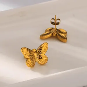 Elegant gold butterfly stud earrings on white ceramic tray with polished finish