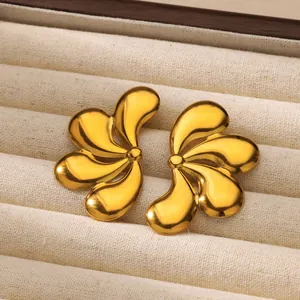 Pendientes dorados de acero inoxidable con forma de pétalo en un joyero de color beige
