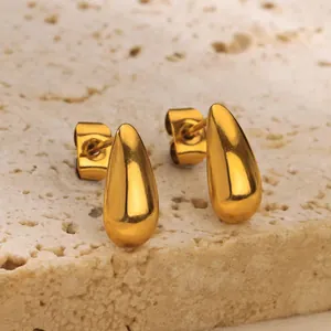 Detailed close-up of golden teardrop stud earrings with polished mirror finish on stone