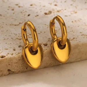 Macro view of polished gold water drop earrings on natural stone texture background