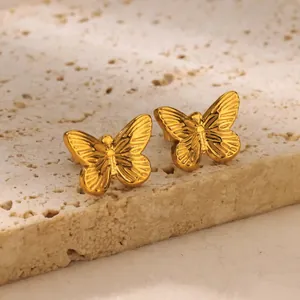 Detailed macro view of gold butterfly stud earrings featuring textured wing patterns