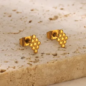 Detailed view of golden triangular beaded cluster earrings on a beige stone background