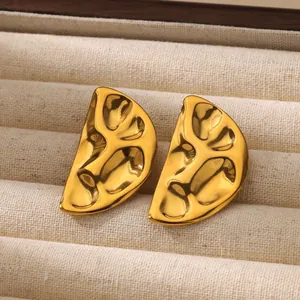 Detalle macro de pendientes geométricos dorados irregulares con textura metálica ondulada