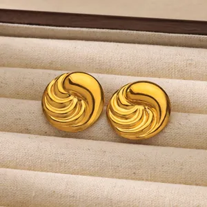 Detalle de pendientes dorados con diseño de espiral en una caja de joyería blanca