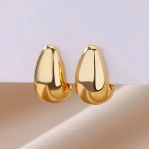 Detalle de pendientes de gota dorados con acabado de espejo pulido en tarjeta de muestra