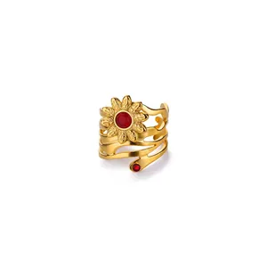 Detailed close-up of golden sunflower ring with red enamel center and wave hollow band