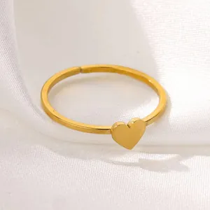 Minimalist gold heart-shaped ring with polished pendant on white silk fabric background