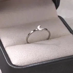Detailed close-up of silver crescent moon ring on a grey velvet jewelry box display