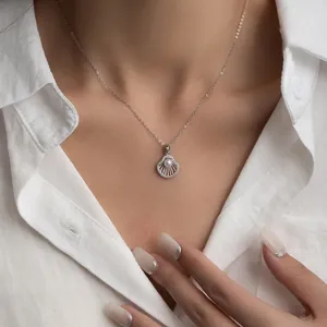Detailed view of scallop shell pendant with pearl and diamonds on silver chain
