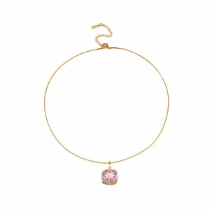 Dettaglio ravvicinato della collana vintage dorata con ciondolo a fiore in smalto viola