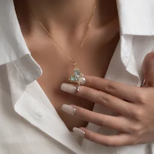 Macro detail of zircon butterfly pendant with blue stones on a gold chain necklace