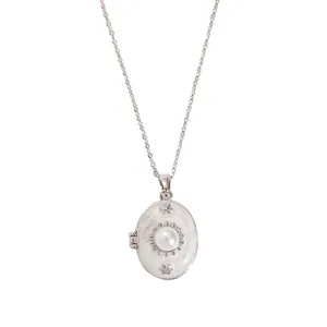 Detail of silver locket necklace with white enamel inlay and center pearl embellishment