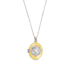 Macro shot of oval locket pendant with enamel flower and pearl on a gold chain