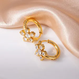 Orecchini a cerchio dorati a fiore con zirconi su sfondo elegante in seta champagne
