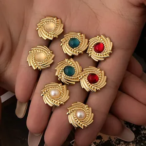 Vintage sunburst gold stud earrings with colorful center stones held in palm