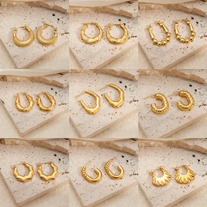 Set of nine diverse gold titanium steel earrings with textured hoop and twist designs