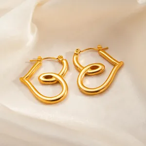 Elegant gold-plated twisted heart stud earrings on beige silk fabric background