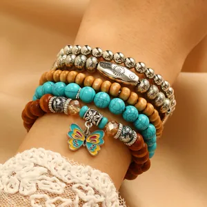 Dettaglio di bracciali boho multistrato con turchese, perle in legno e ciondolo farfalla
