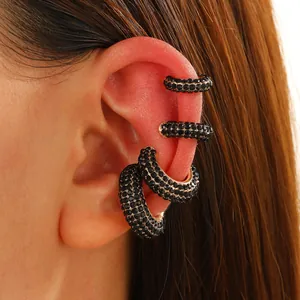 Detailed close-up of four black rhinestone ear cuffs set on gold-plated metal base