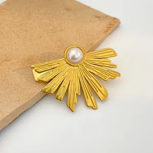 Vintage golden sunburst hair clip featuring a white pearl center on a brown textured mat
