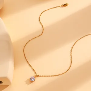 Détail macro d'un collier doré avec pendentif solitaire rond en zircon et serti à six griffes