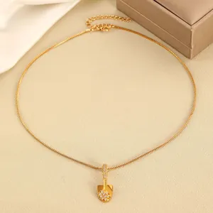 Elegant gold shovel pendant necklace with sparkling diamonds on a textured background