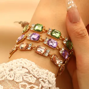 Dettaglio di braccialetti con gemme rettangolari colorate su modella con pizzo