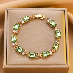 Dettaglio del bracciale dorato con pietre verdi taglio smeraldo e strass bianchi
