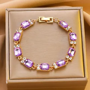 Dettaglio di un bracciale dorato con pietre quadrate viola e accenti di diamanti