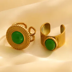 Details von vergoldeten Vintage-Ringen mit grünen Ovalsteinen auf beigem Satin