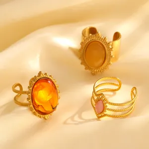 Detail von vergoldeten Vintage-Ringen mit Bernstein und rosa Edelsteinen auf Seide
