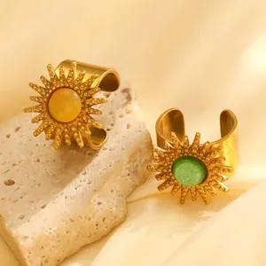 Detailansicht luxuriöser goldener Sonnenblumenringe mit Edelsteinen auf Seide