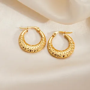 Golden round hoop earrings with hammered texture on elegant beige silk background