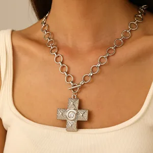 Dettaglio di una collana vintage con croce d'argento, spirale e chiusura a barra OT