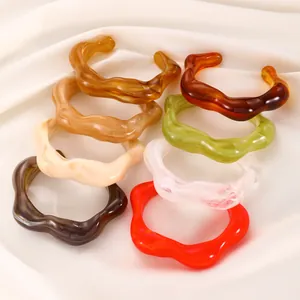 Macro shot of colorful marbled resin open bangles on white silk fabric background
