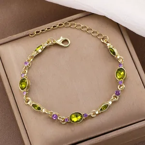 Elegant gold-plated bracelet with olive green stones and purple crystals on jewelry box