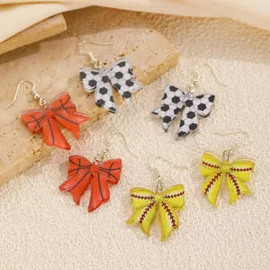 Macro detail of acrylic bow earrings featuring soccer, basketball and baseball patterns