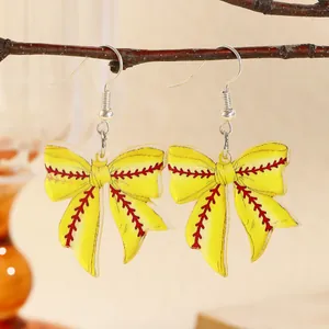 Detail of yellow baseball-style bow earrings made of acrylic on a natural branch