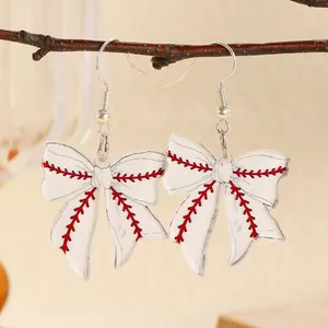 Detail view of acrylic bow earrings featuring classic red baseball stitching pattern