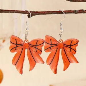Close-up of basketball pattern bow drop earrings hanging on a natural wooden branch