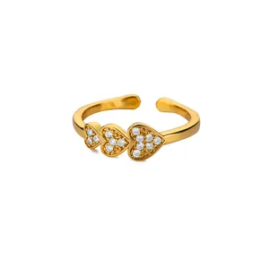 Macro detail of three linked golden hearts with white zircon inlay on adjustable ring